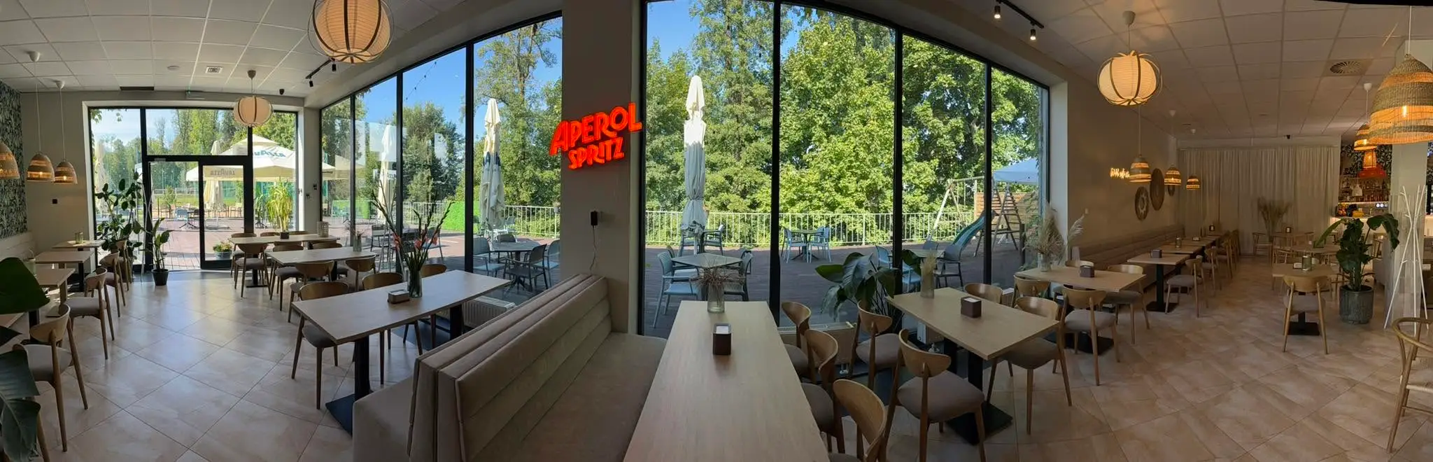 Sala restauracji Widok — stoliki i przeszklona ściana z widokiem na zieleń
